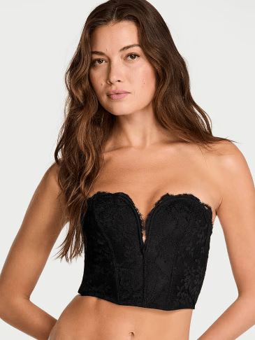 Upper view of a woman wearing Victoria's Secret black V-cropped corset top on a light grey background.