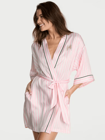 Front view of a woman wearing Victoria's Secret signature stripe silky robe on a light grey background.