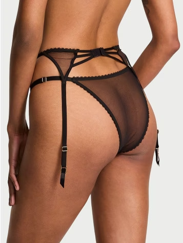 Back view of a woman wearing Victoria's Secret black transparent garters and hosiery bottom piece on a light grey background