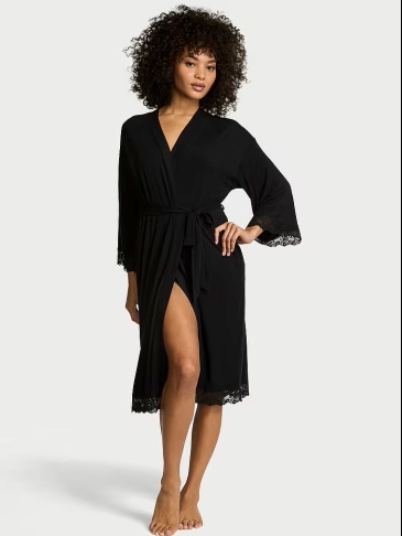 Full body view of a woman wearing Victoria's Secret black modal lace-trim robe on a light grey background.