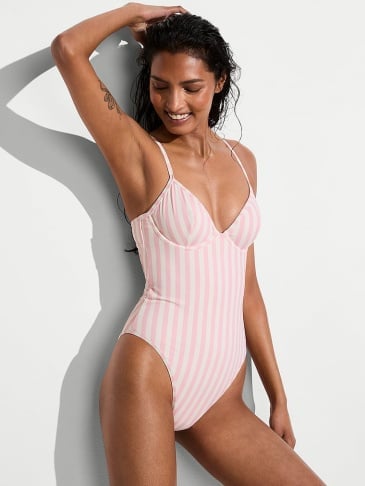 Front view of a woman wearing Victoria's Secret signature stripe one-piece swimsuit on a light grey background.